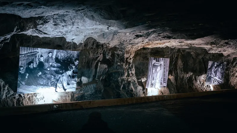 Store, opplyste fotografier av gruvearbeidere hengt opp på fjellveggen inne i Kongens gruve.