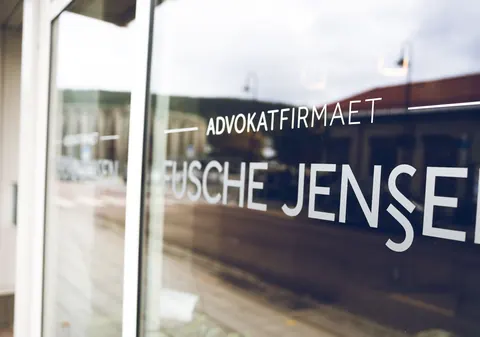 Vindusdekor med navnet Advokatfirmaet Fusche Jensen på en glassfasade.